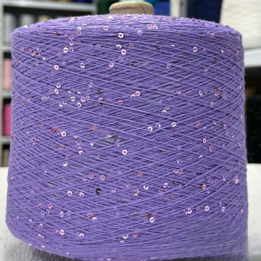 Spool of purple yarn with sequins on a white background