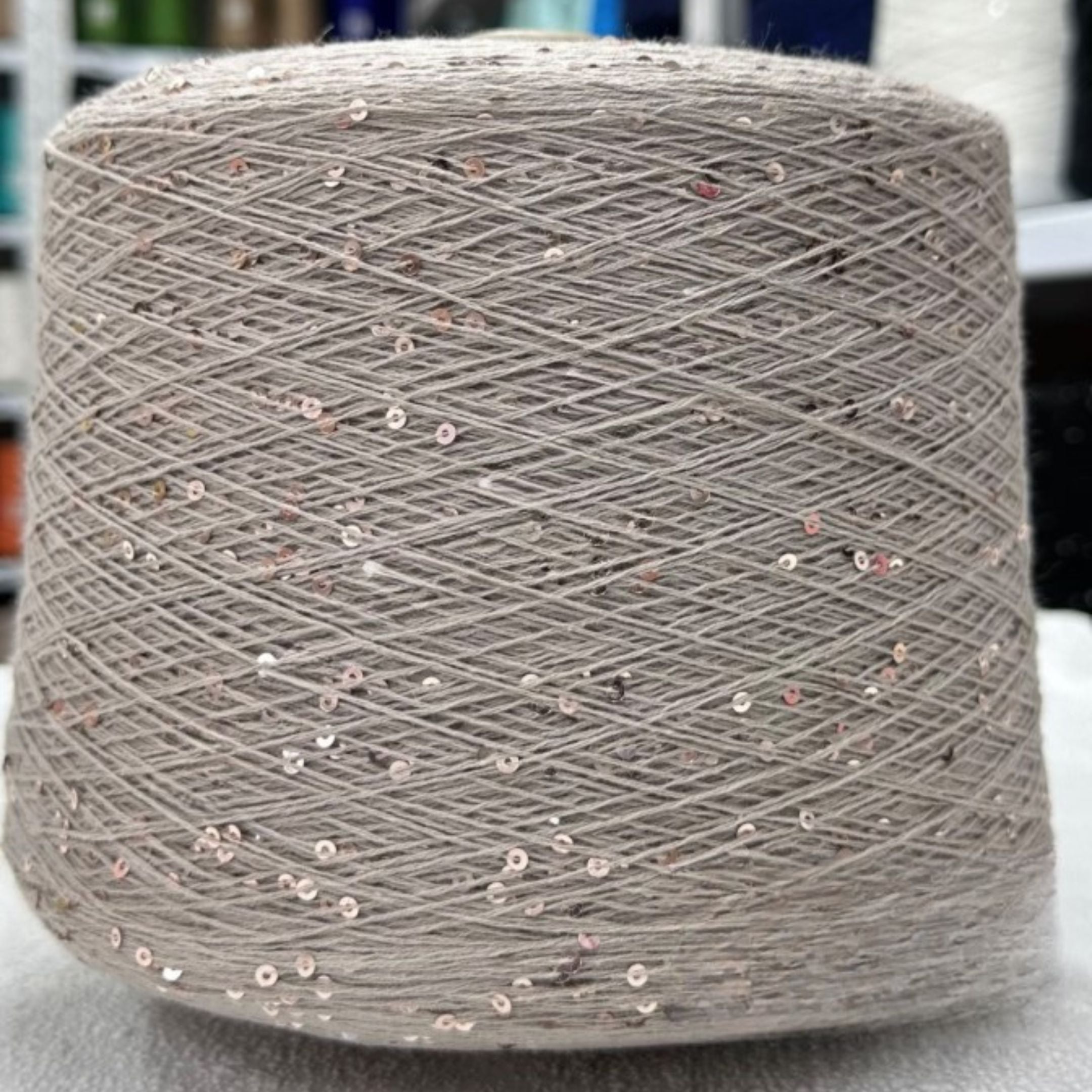 Spool of gray yarn with small specks on a white surface