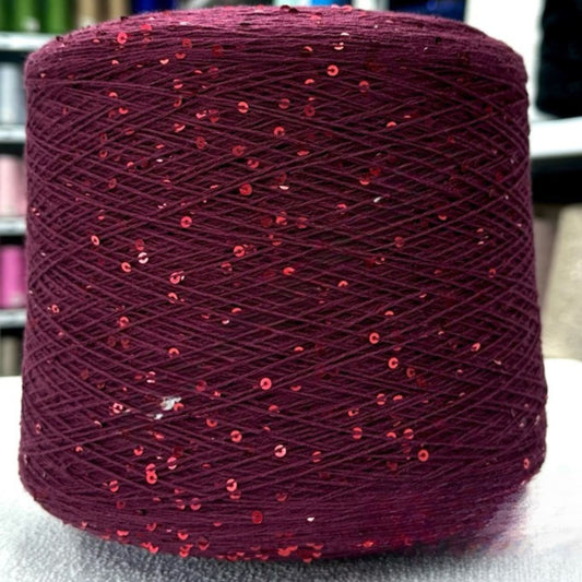 Spool of purple yarn with red sequins on a neutral background