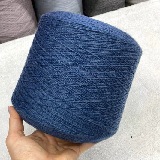 Blue merino yarn ball held by a hand on a light background