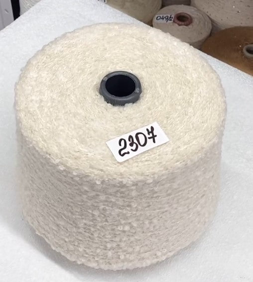 White yarn spool with a label on a white background of luxury textured alpaca boucle colors