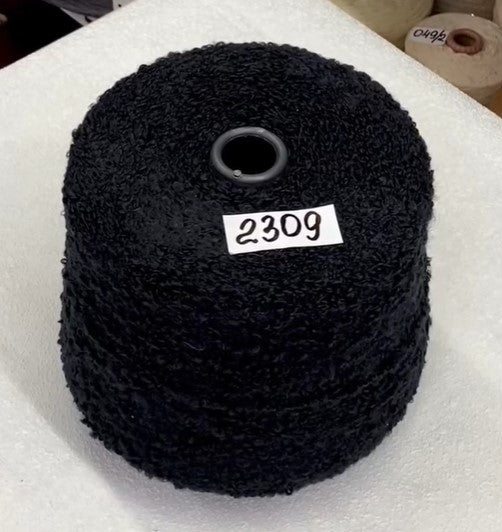 Black yarn roll with label '2309' on a white foam block Beautiful texture Italian boucle in soft daylight