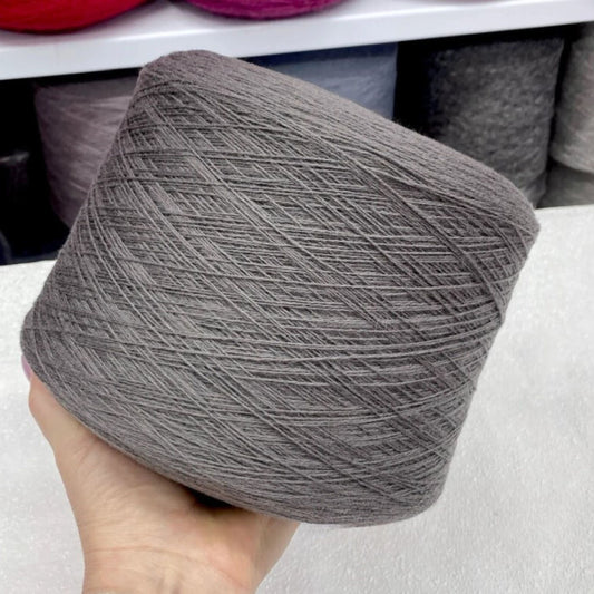 Gray yarn ball held in a hand with blurred background