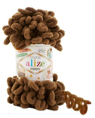 Brown yarn ball on top of a container labeled 'alize puffy 321' with more yarn wrapped around it.
