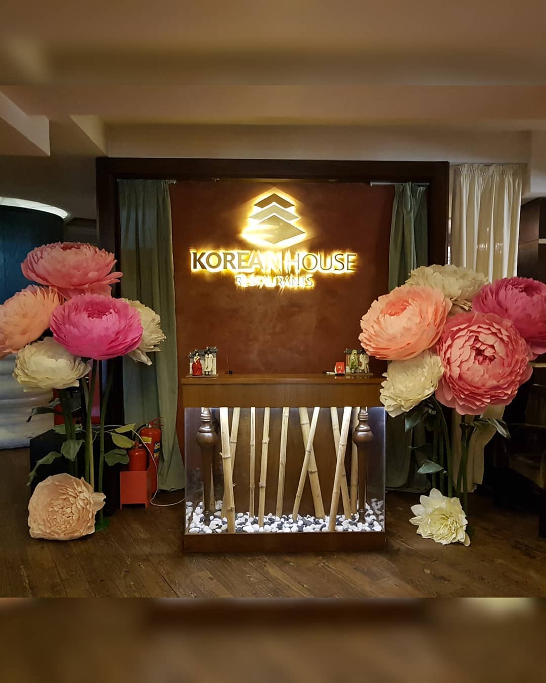 Vibrant giant paper peony flowers in magenta, hot pink, purple and cream standing at the entrance of  Large 65cm handmade peonies creating an impressive welcome decoration for events and restaurants.