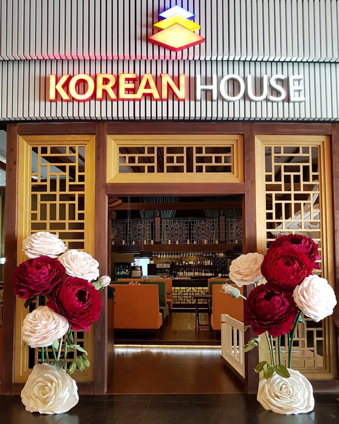 Stunning giant paper peony arrangements in deep red, burgundy and white flanking the entrance to  restaurant. Oversized handmade crepe paper flowers perfect for restaurant and wedding decor.