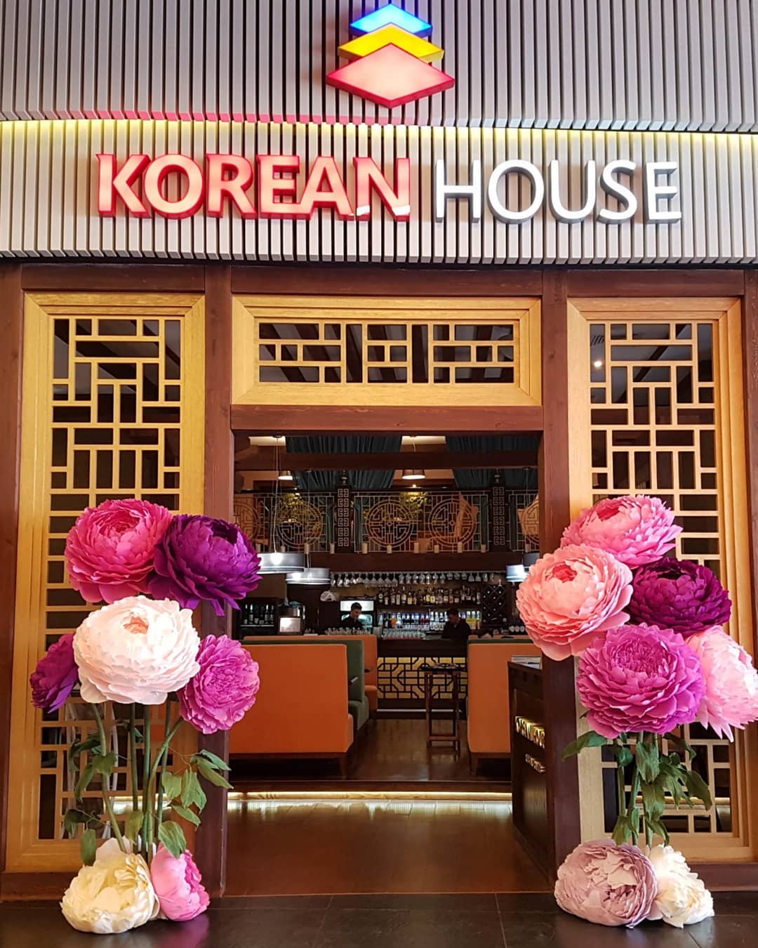 Giant paper peony flowers in soft pink, peach and cream decorating the entrance of restaurant. Beautiful large handmade peonies used as luxurious interior and event decor.