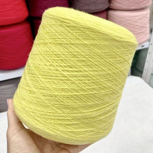 Yellow merino yarn ball held in hand with colorful yarn balls in the background