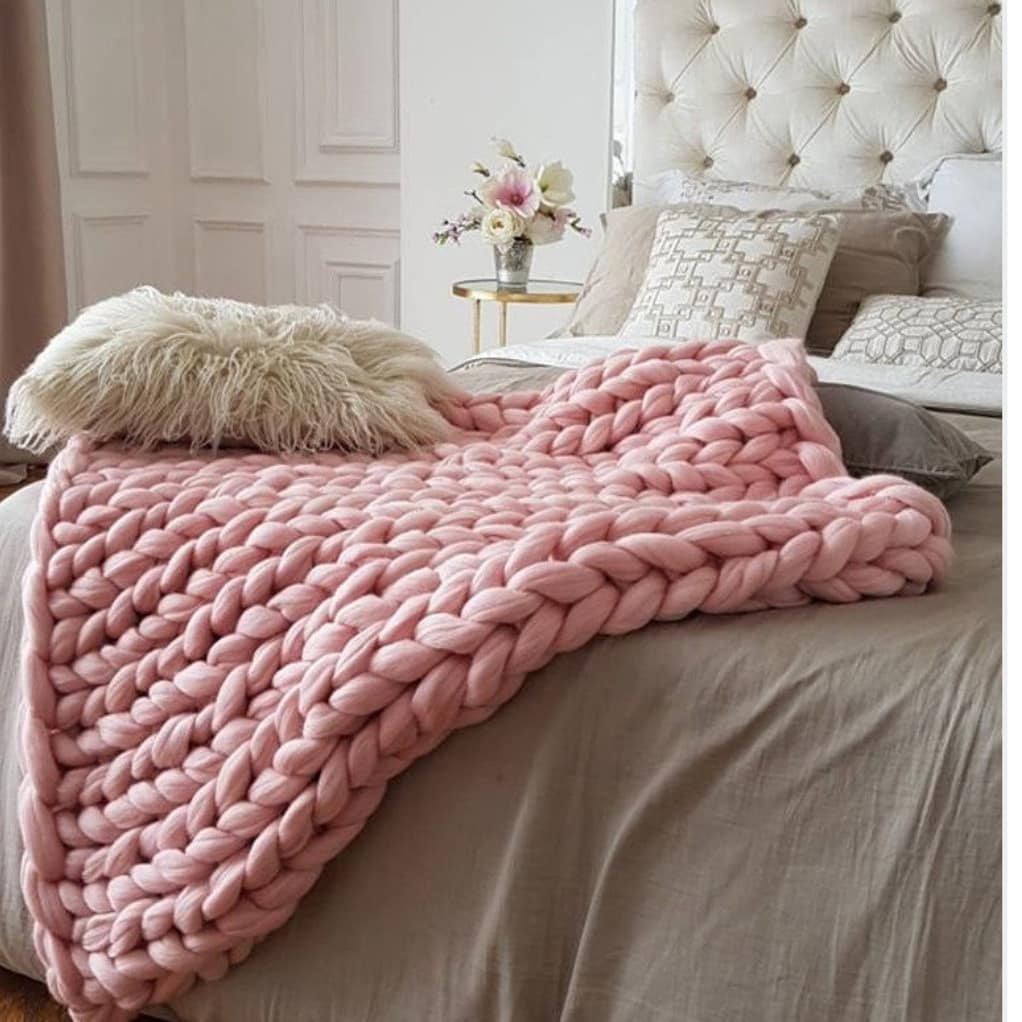 Beige oversized chunky blanket stacked on wooden stool