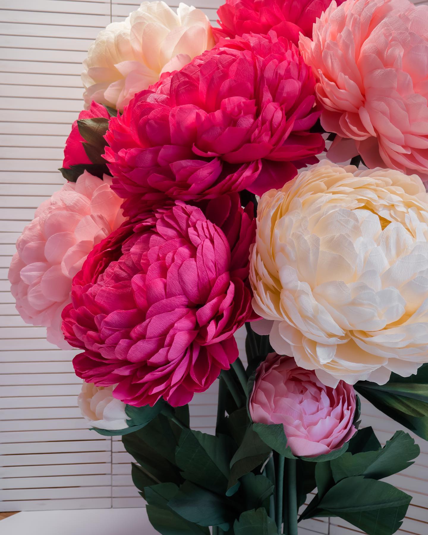 Close-up of giant paper peony bouquet featuring rich magenta, bright pink and soft cream flowers. Premium Italian crepe paper peonies perfect for photo zones, parties and elegant home decoration.