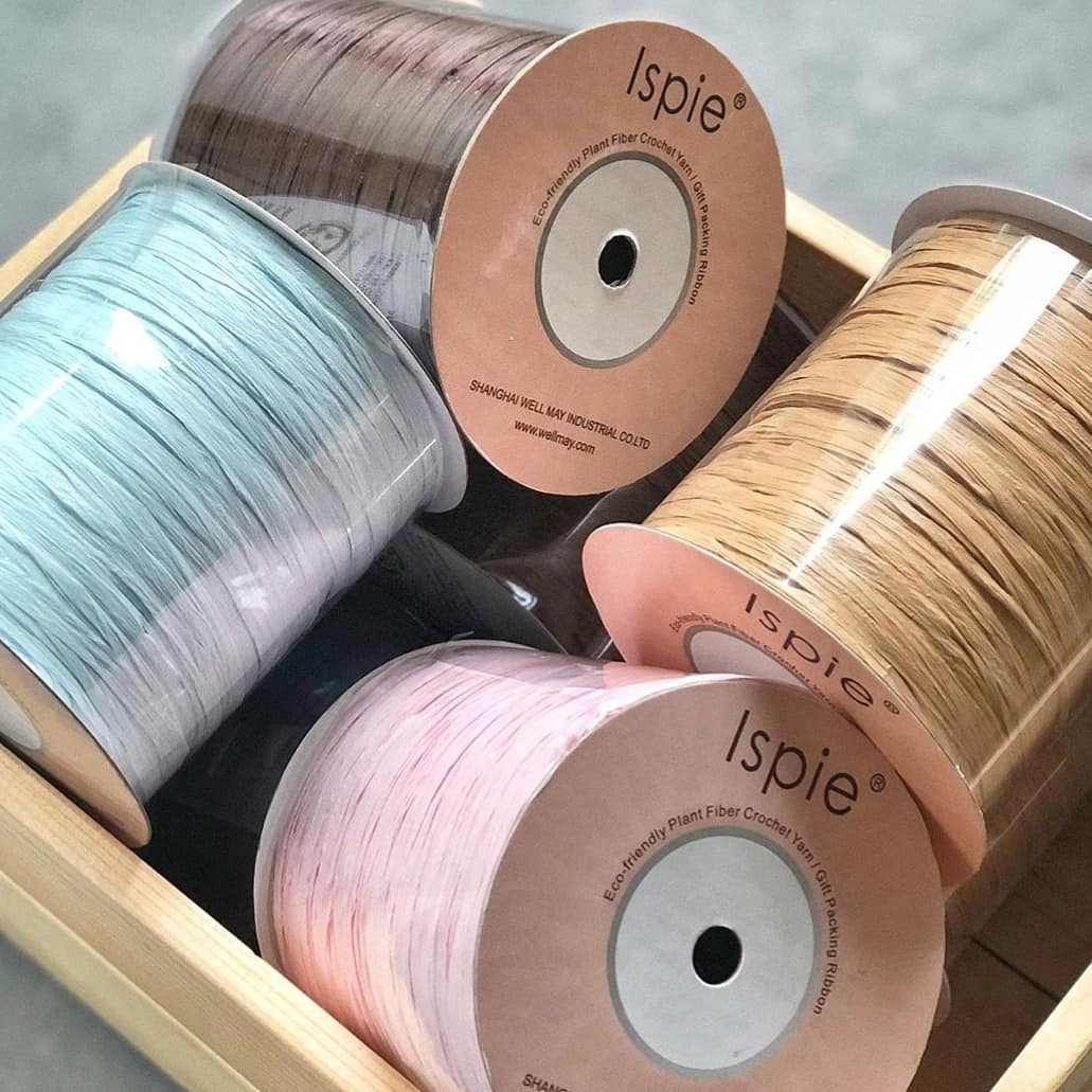 Close-up of ISPIE Eco-friendly Plant Fiber Crochet Yarn spools with official labels – premium genuine rayon raffia for structured bags and hats
