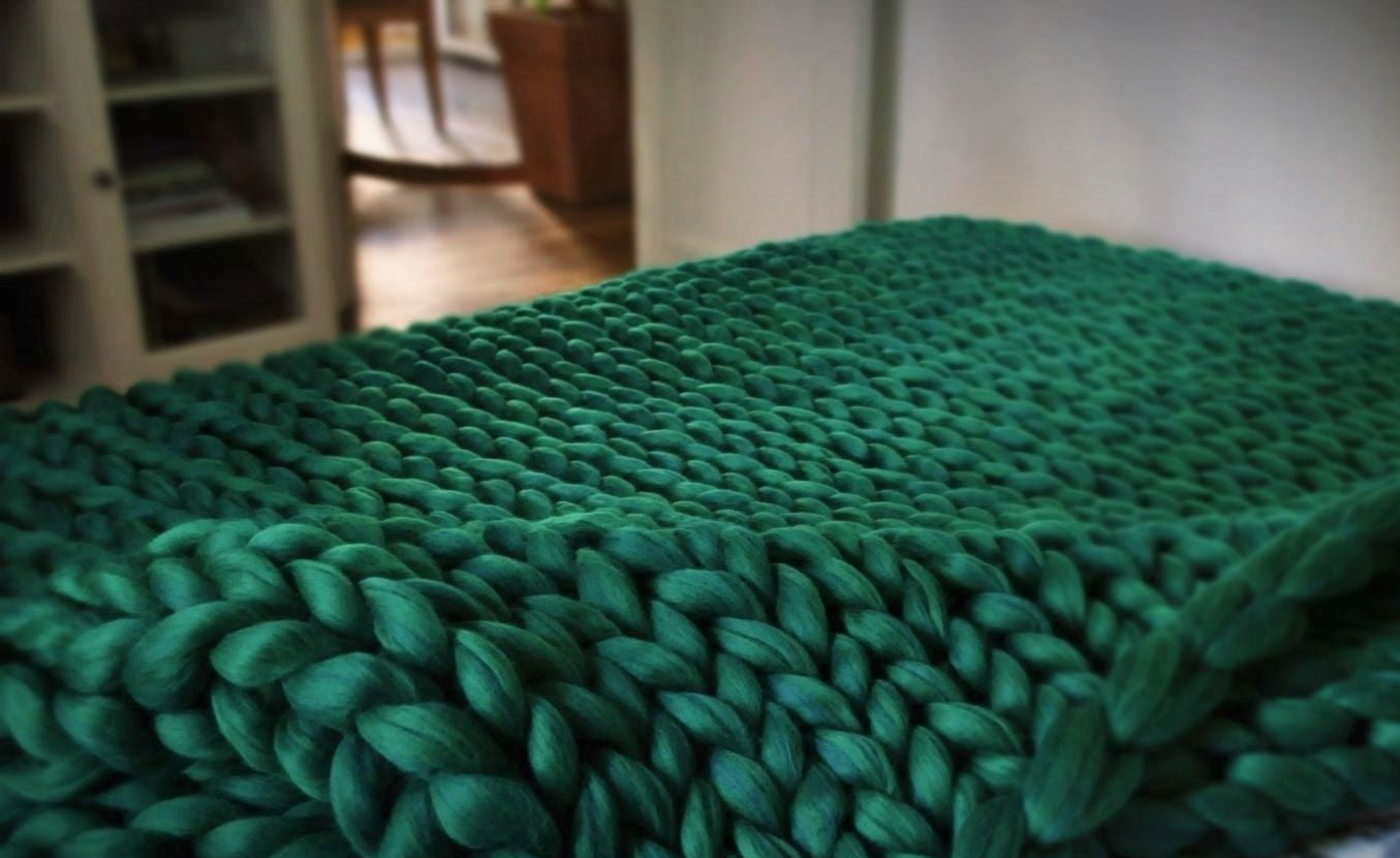 Super bulky arm-knitted merino blanket on chair